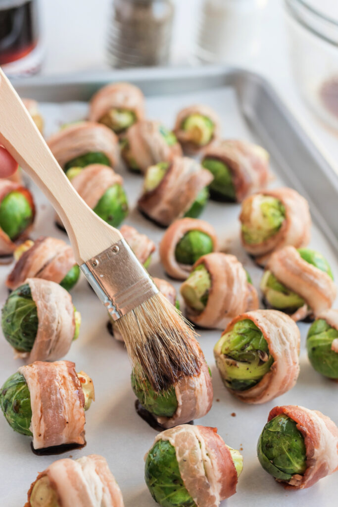 brushing bacon wrapped sprouts with maple mixture