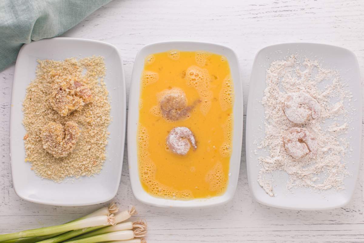 shrimp being dipped in flour, egg, and bread crumbs