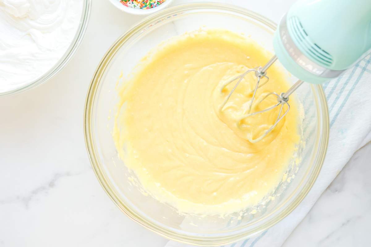 cake mix, pudding, and milk mixed together in a bowl