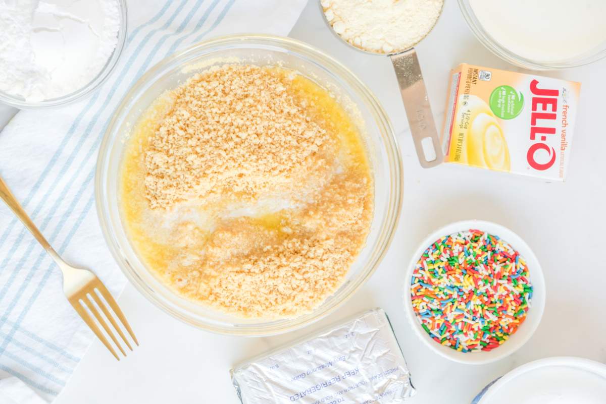 butter being added to crushed oreos in a bowl