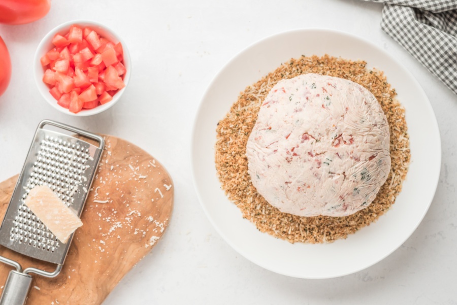 cheese ball placed on a plate with bread crumbs