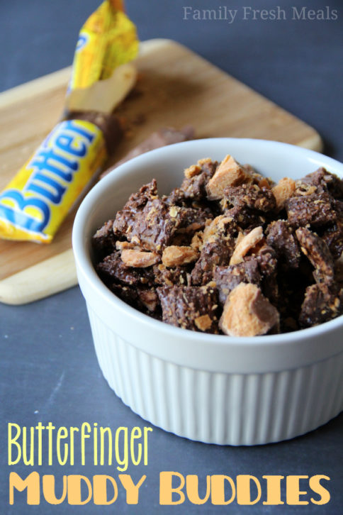 Butterfinger Muddy Buddies Recipe served in a white dish, with an open butterfinger candy car in the background