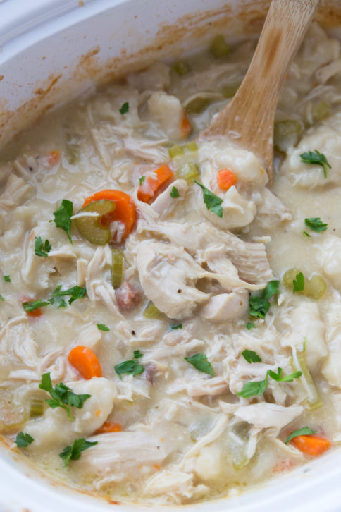 Chicken and Dumplings in a slow cooker with a wooden spoon