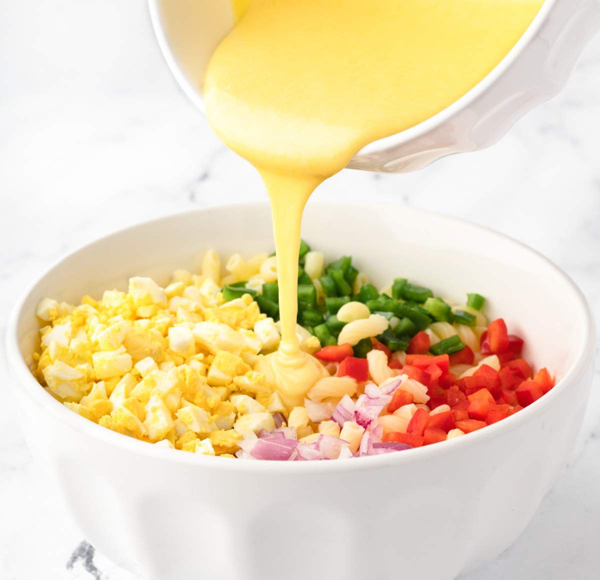 pouring dressing over pasta salad