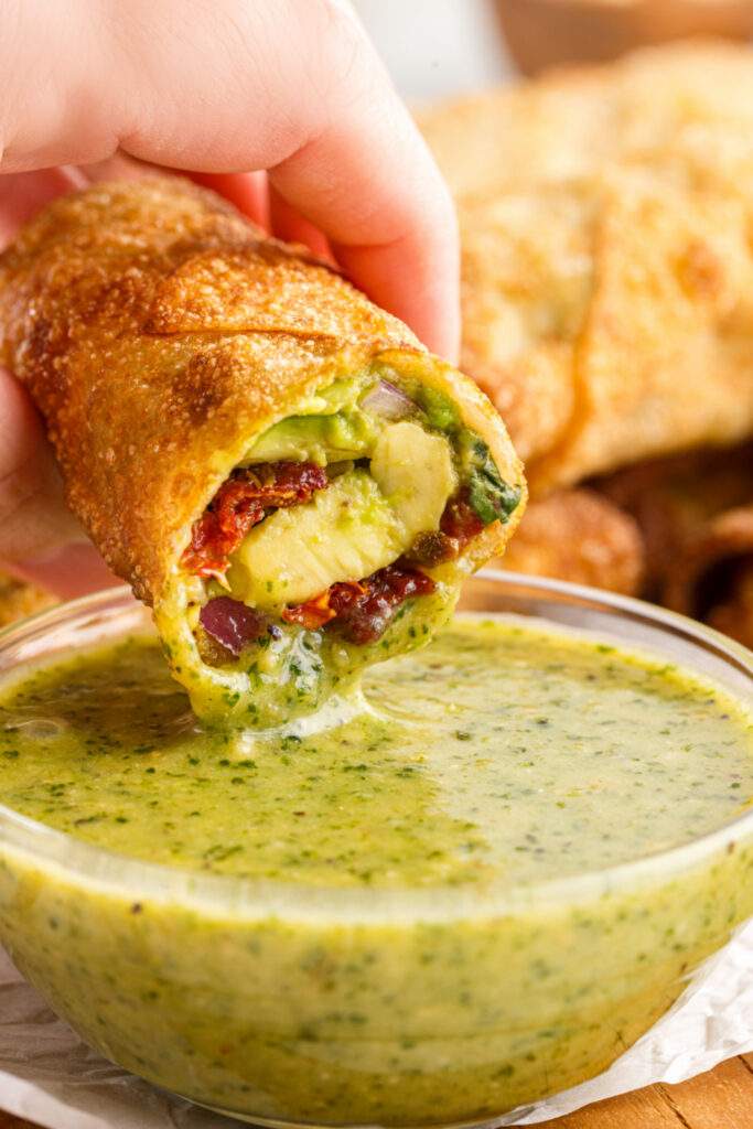 dipping Copycat Cheesecake Factory Avocado Egg Roll in sauce