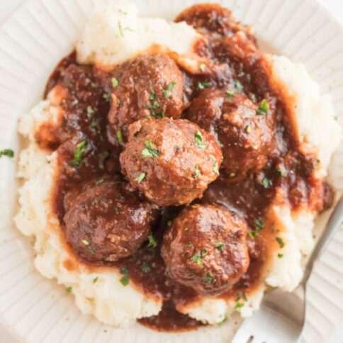 Crockpot Guinness Glazed Meatballs on a plate with mashed potatoes