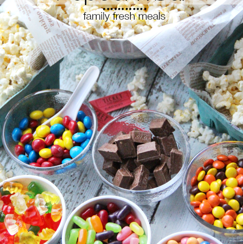 Large bowl of Popcorn surrounded by small bowls of different candies