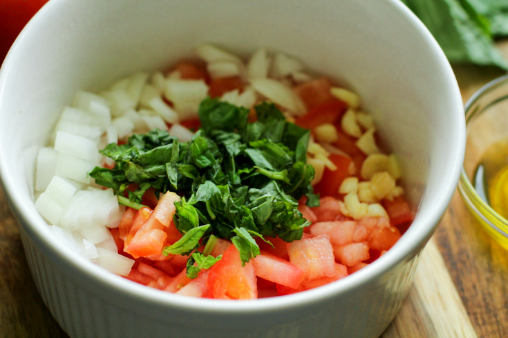 Easy Fresh Bruschetta Recipe - Chopped tomatoes, onion, garlic and basil in a white bowl