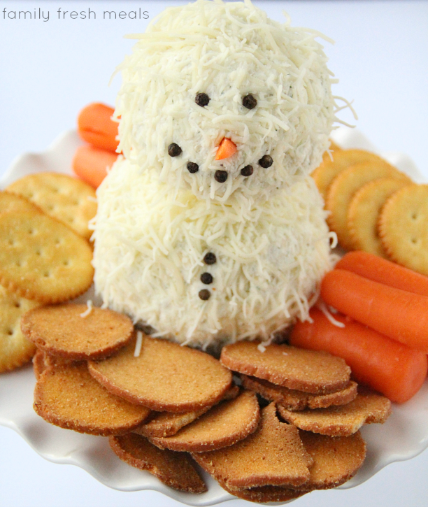 Holiday Ranch Cheese Ball that looks like a snowman on a platter with crackers and carrots