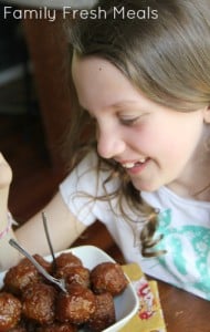 Child smiling at a bowl of Honey Garlic Crockpot Meatballs