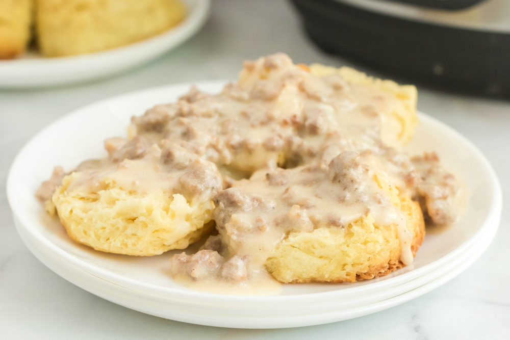 Instant Pot Sausage Gravy served over biscuits on a white plate