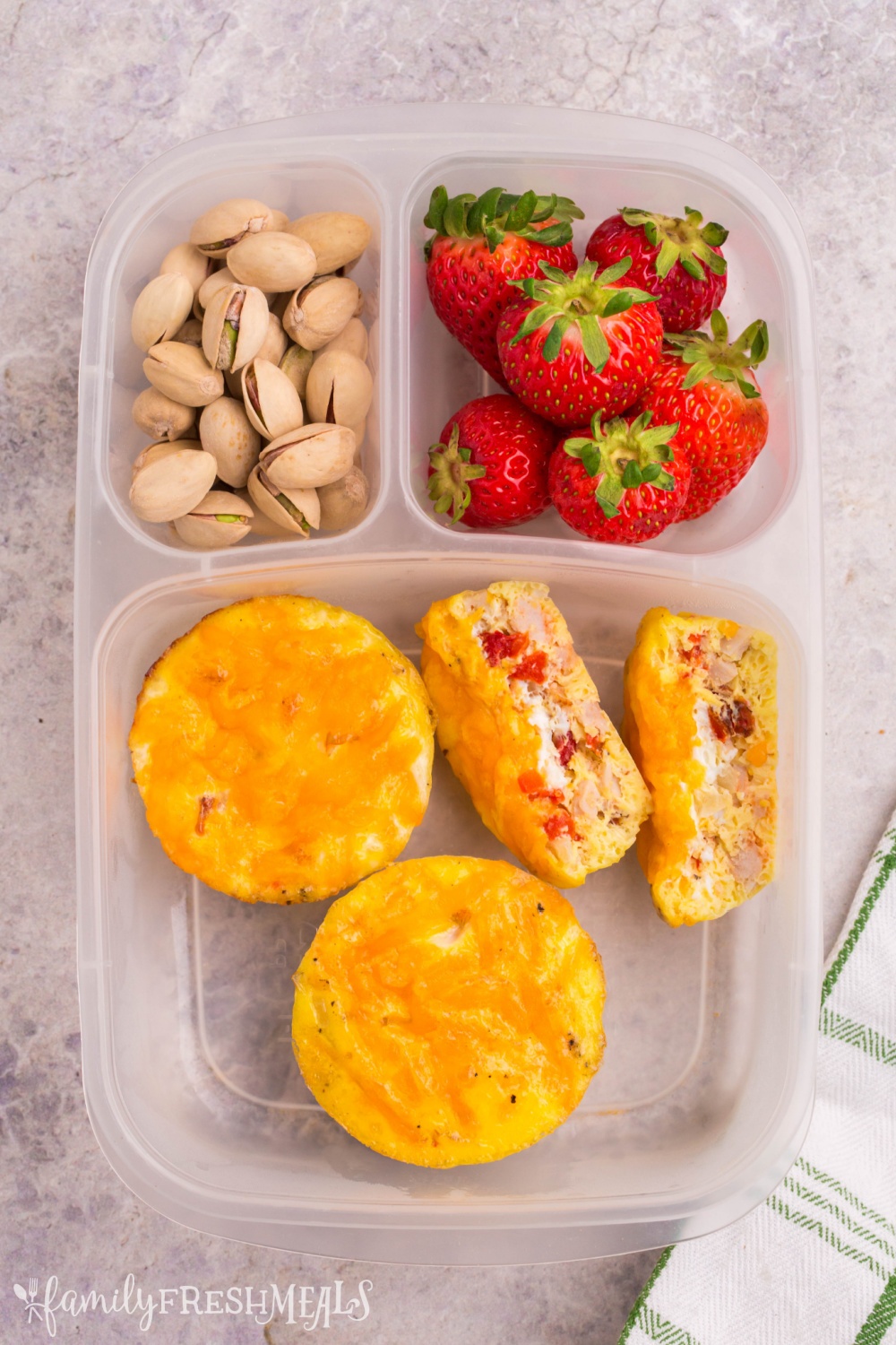 Lunchbox packed with egg cups, strawberries and pistachios 