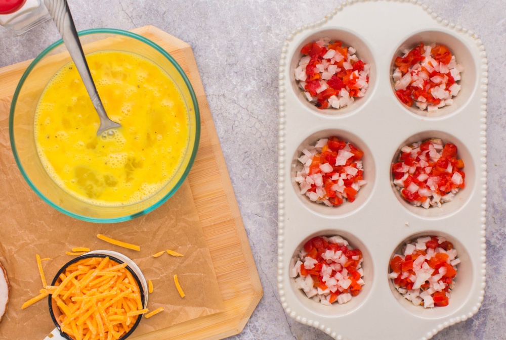 adding chopped onion and peppers into muffin tin