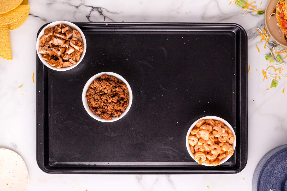 meats in bowls on taco board