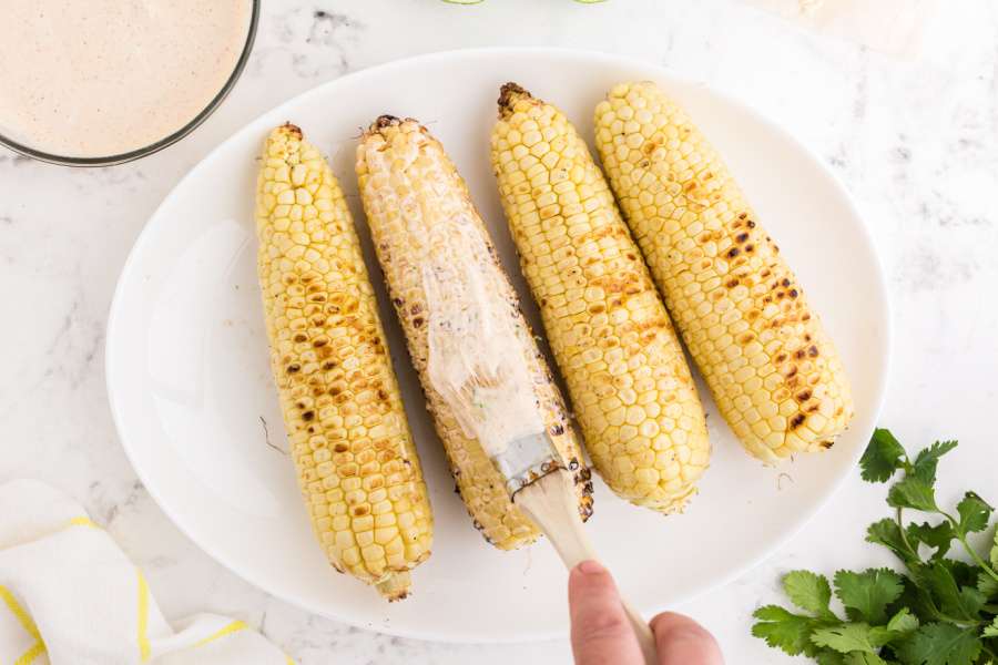 brushing corn with sauce