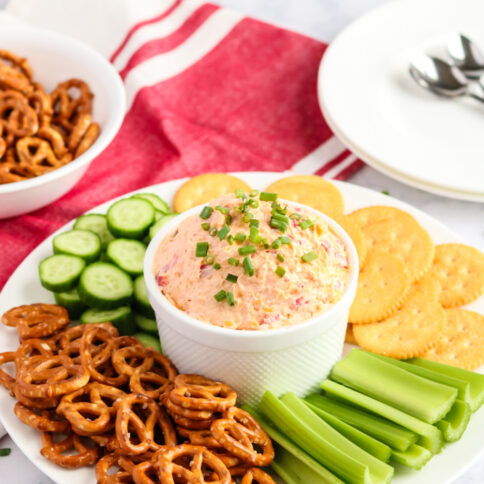 Pimento Cheese Spread recipe in a bowl with pretzels, cracker, celery and cucumbers