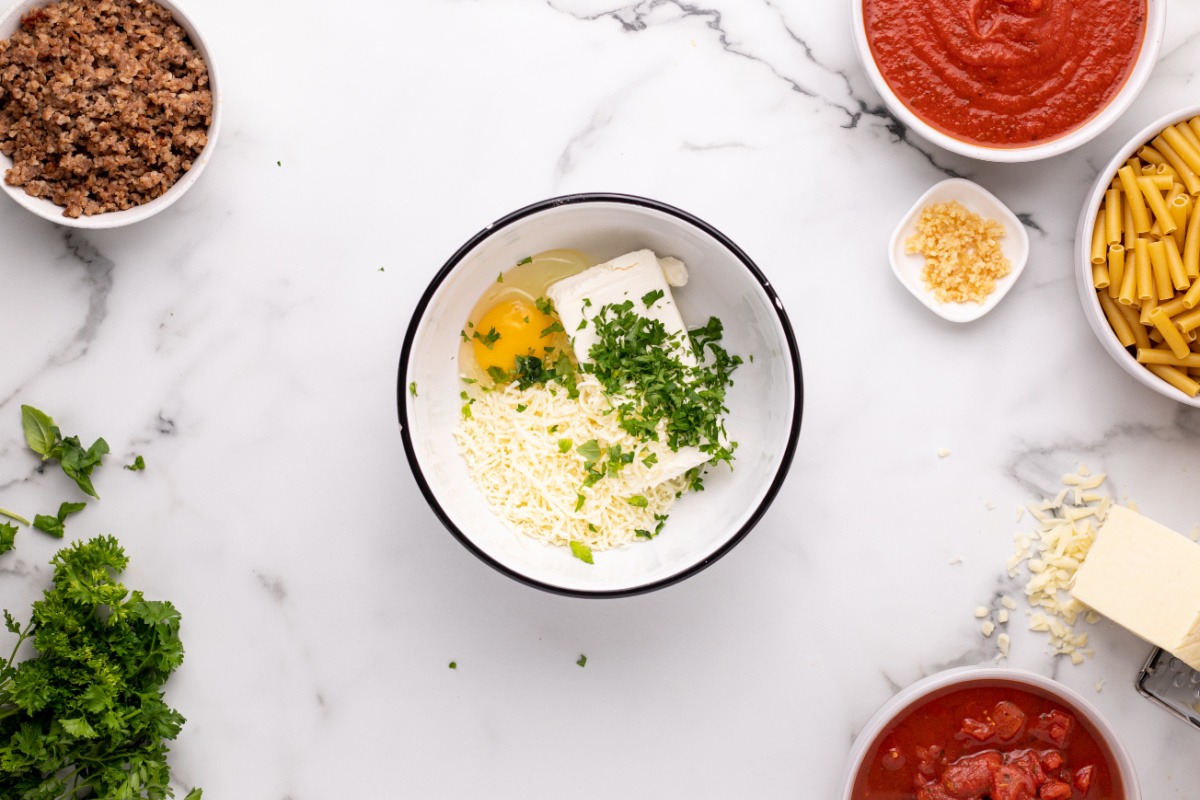 cream cheese, eggs, parmesan cheese, basil, and parsley in a bowl