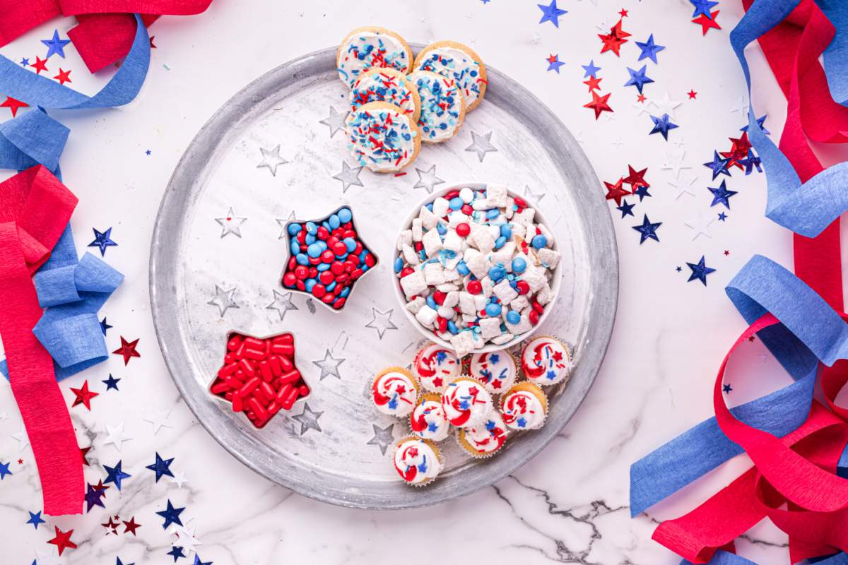 candies, muddy buddy and cookies being added to tray