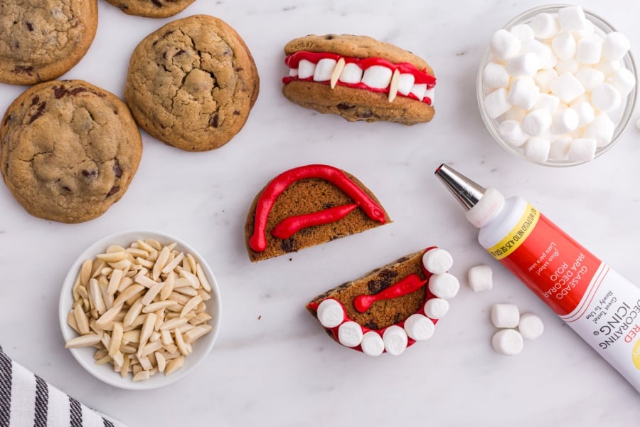 showing how to put marshmallow teeth and icing on cookie 