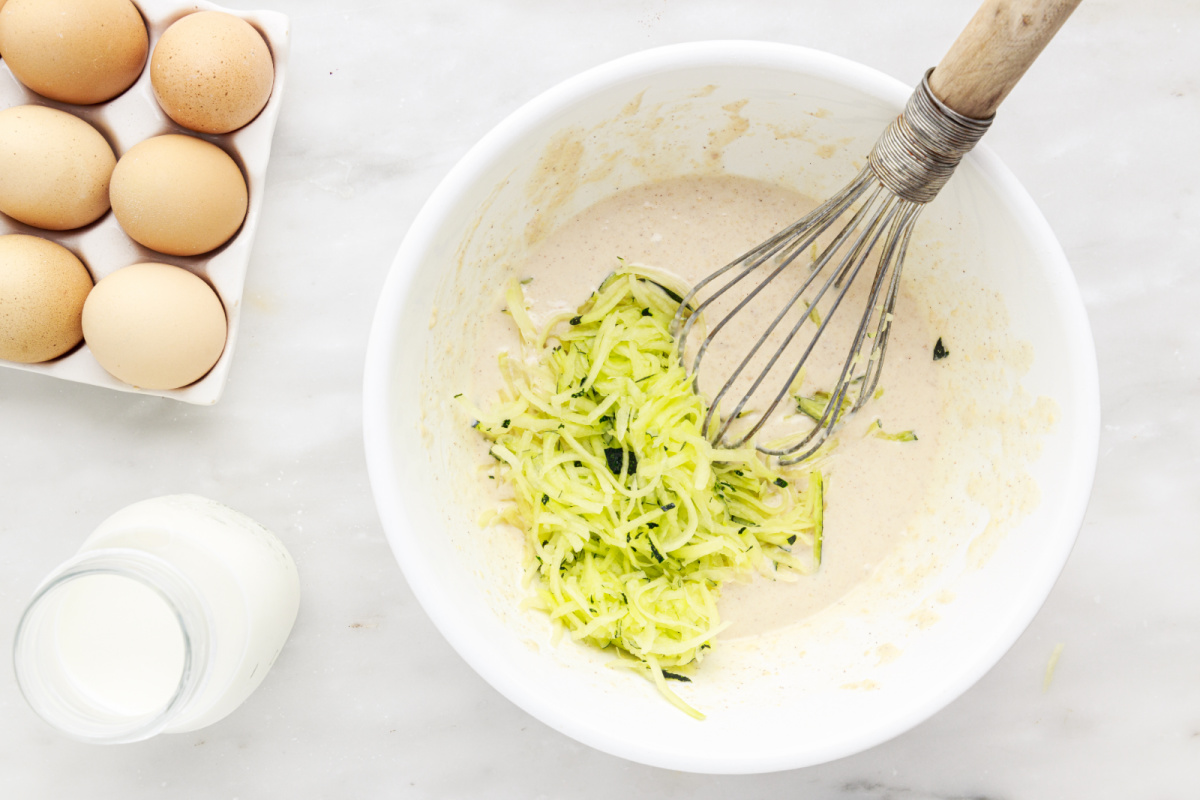 eggs, milk and shredded zucchini in a bowl