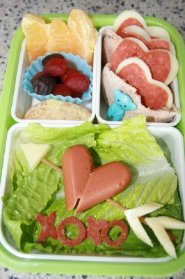 Valentines bento lunch box - hotdog heart, mini pitas sandwiches, fresh fruit and pepperoni cut into mini x's and o's