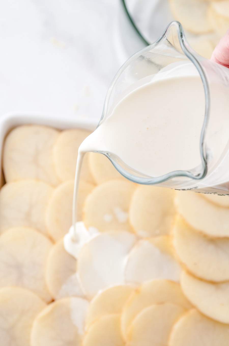 cream being poured over potato slices