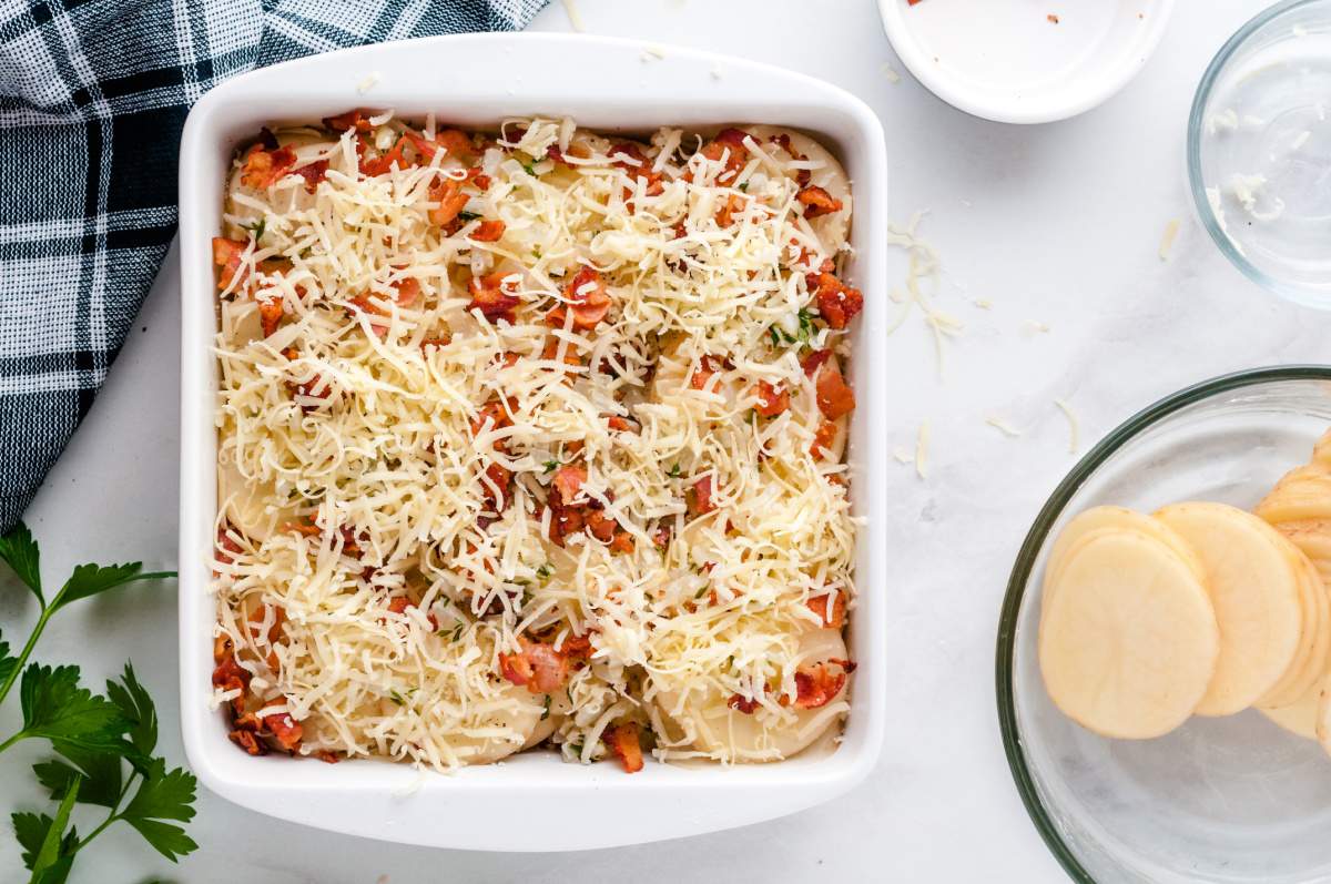 unbaked cheesy scalloped potatoes with bacon in baking dish