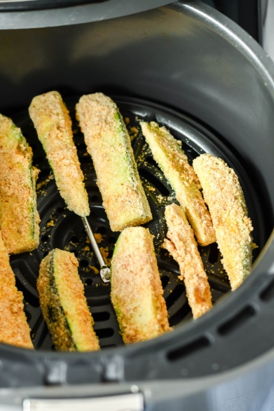 uncooked zucchini fries in air fryer basket